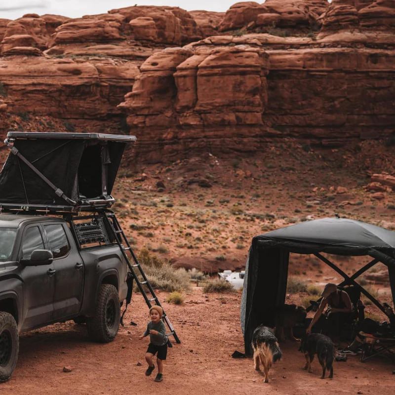 freespirit-recreation-foundation-series-hub-v2-black-open-front-view-rolled-up-doors-with-dog-and-persons-in-desert