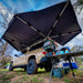 overland-vehicle-systems-nomadic-270-awning-driverside-open-rear-corner-view-on-toyota-tacoma-in-nature-camp