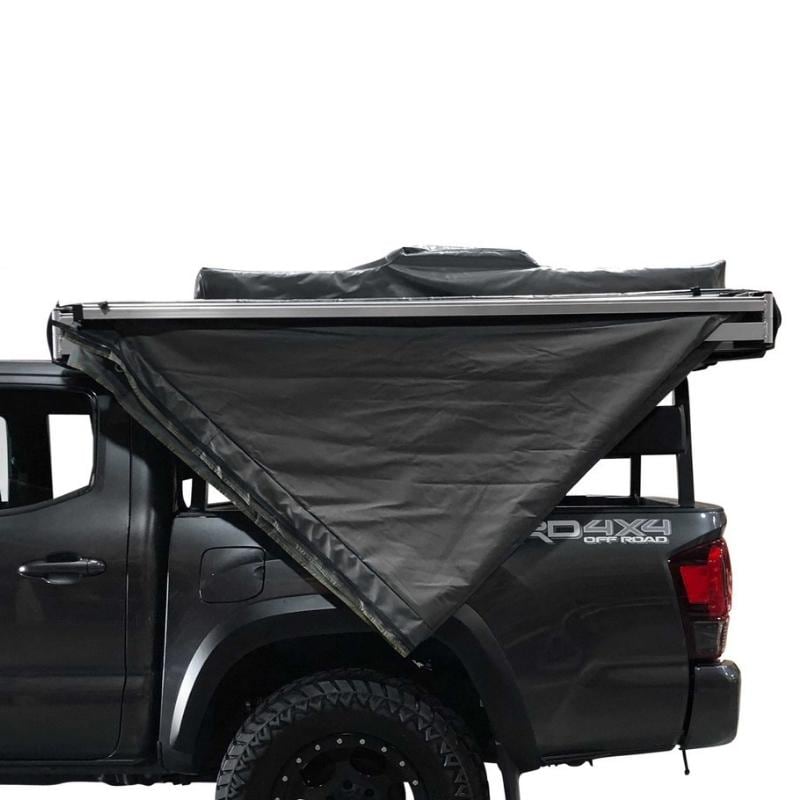 overland-vehicle-systems-nomadic-270-awning-driverside-semi-open-and-folded-side-view-on-toyota-tacoma-in-nature