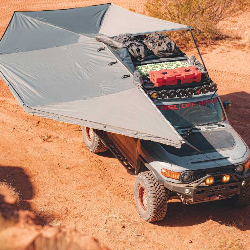 overland-vehicle-systems-nomadic-270-awning-passenger-side-open-drone-view-on-toyota-fj-cruiser-in-desert