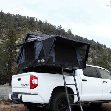 overland-vehicle-systems-xd-everest-cantilever-aluminum-roof-top-tent-gray-body-black-rainfly-open-front-corner-view-with-ladder-on-toyota-tundra-in-nature