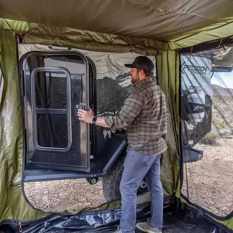 23zero-bushman-straight-pull-awning-90in-x-98in-awning-room-open-interior-view-with-person-vehicle-door-in-nature