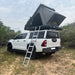 eezi-awn-blade-40th-edition-hard-shell-roof-top-tent-open-rear-corner-view-on-vehicle-with-extended-ladder-in-nature