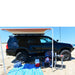 eezi-awn-k9-roof-rack-for-toyota-4runner-4th-gen-side-view-with-awning-and-baby-on-camping-chair-at-the-beach