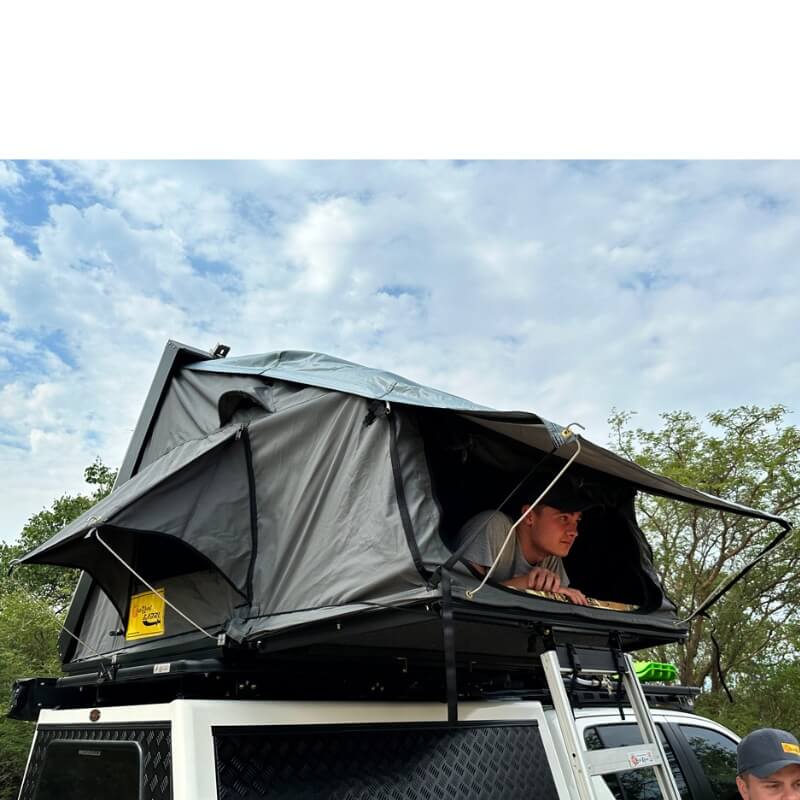 eezi-awn-sabre-hard-shell-roof-top-tent-open-rear-corner-view-on-vehicle-with-person-and-ladder-in-nature