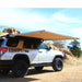 eezi-awn-swift-awning-beige-open-rear-corner-view-freestanding-on-toyota-4runner-in-nature