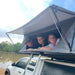 eezi-awn-sword-hard-shell-roof-top-tent-open-close-up-view-on-vehicle-with-persons-in-nature