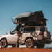 eezi-awn-sword-hard-shell-roof-top-tent-open-side-view-on-vehicle-with-person-and-ladder-in-desert