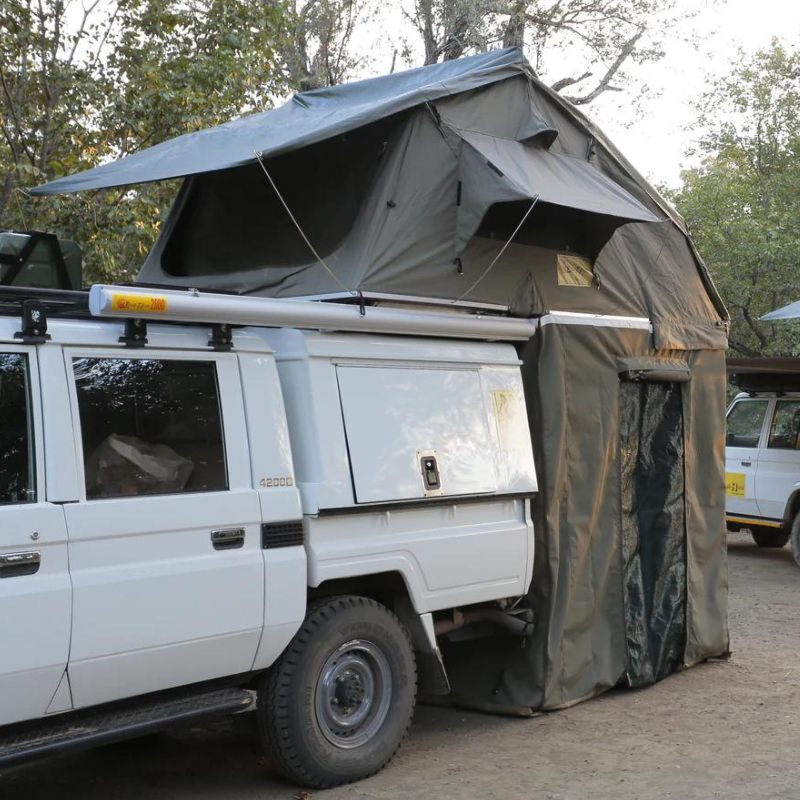 eezi-awn-xklusiv-soft-shell-roof-top-tent-olive-open-corner-view-on-vehicle-with-extended-room-in-nature