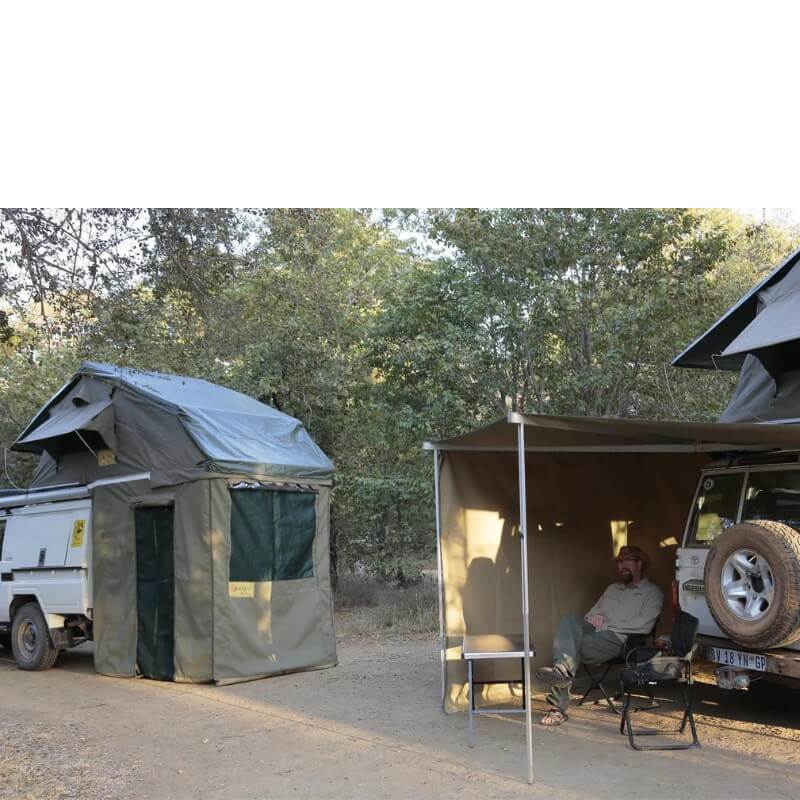 eezi-awn-xklusiv-soft-shell-roof-top-tent-olive-open-rear-corner-view-on-vehicles-with-extended-room-and-awning-in-nature