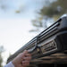 freespirit-recreation-aspen-v2-xl-hard-shell-roof-top-tent-black-closed-close-up-view-with-hand-holding-the-latch-in-nature