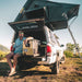national-luna-legacy-smart-qc-fridge-and-freezer-side-view-in-vehicle-with-person-truck-cap-and-roof-top-tent-in-terrain