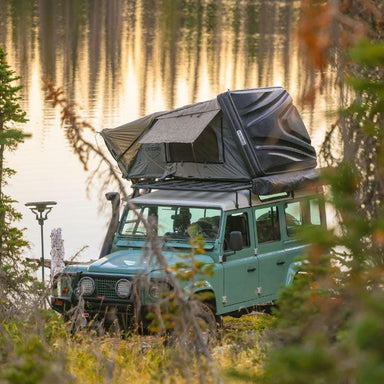overland-vehicle-systems-bushveld-hard-shell-roof-top-tent-open-on-land-rover-defender-in-nature