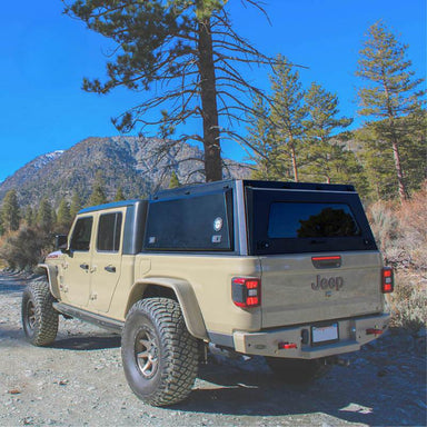 overland-vehicle-systems-expedition-truck-cap-for-jeep-gladiator-black-closed-rear-corner-view-in-terrain