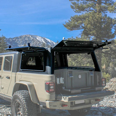 overland-vehicle-systems-expedition-truck-cap-for-jeep-gladiator-black-open-rear-corner-view-in-nature