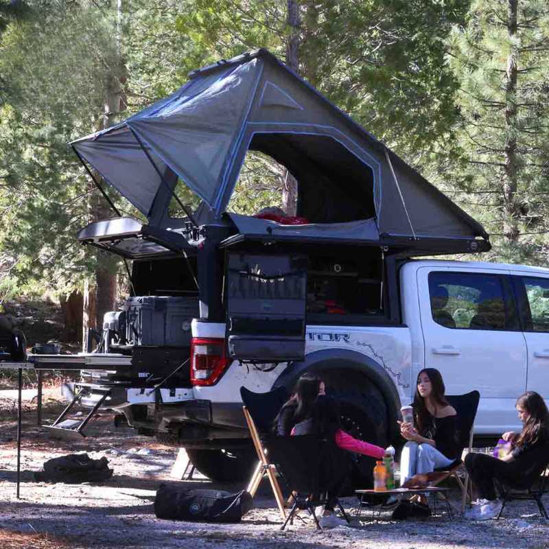 overland-vehicle-systems-magpak-camper-shell-roof-top-tent-for-ford-f-150-open-rear-corner-view-on-vehicle-with-people-in-nature