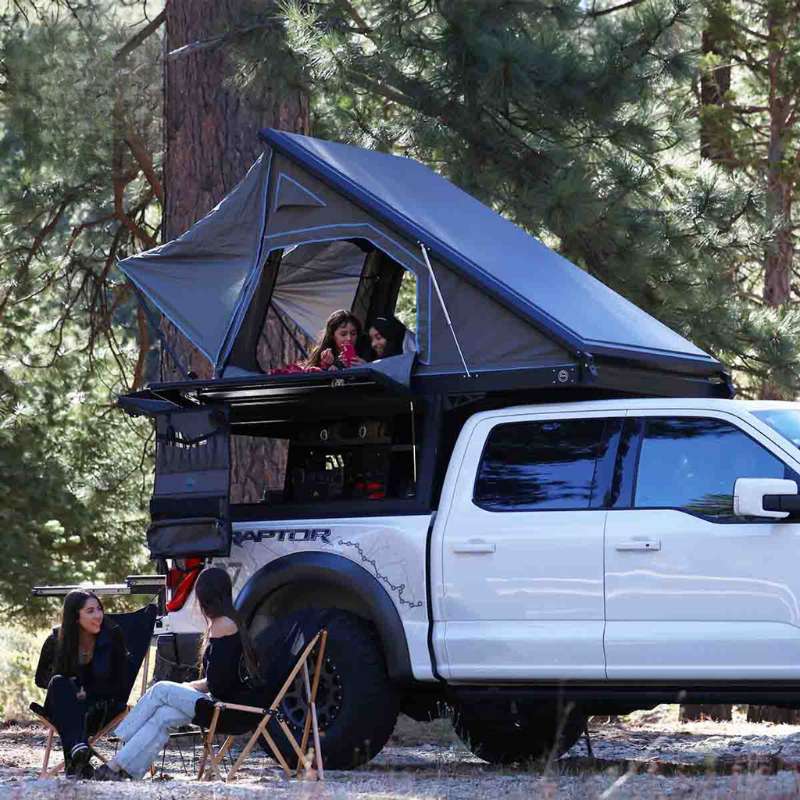 overland-vehicle-systems-magpak-truck-camper-for-toyota-tundra-open-side-view-on-vehicle-with-people-in-nature