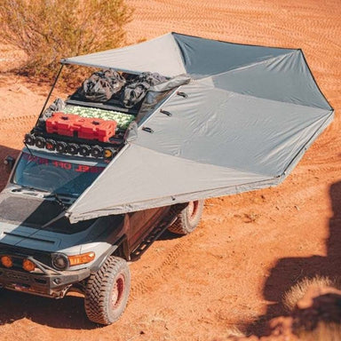 overland-vehicle-systems-nomadic-270-awning-driver-side-open-drone-view-on-toyota-fj-cruiser-in-desert