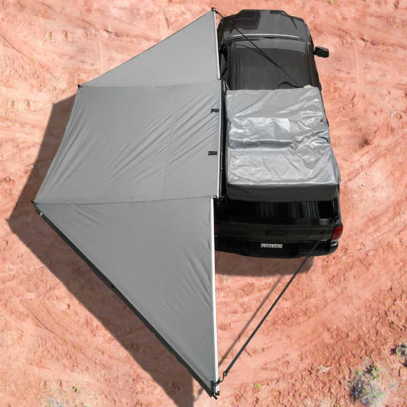 overland-vehicle-systems-nomadic-awning-180-driver-side-dark-gray-open-drone-view-on-toyota-tacoma-in-desert