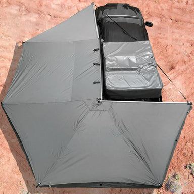 overland-vehicle-systems-nomadic-awning-270-for-mid-high-roofline-vans-driver-side-open-drone-view-on-toyota-tacoma-in-desert