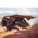 overland-vehicle-systems-nomadic-awning-270-passenger-side-gray-open-on-toyota-fj-cruiser-in-nature-with-person-using-fridge