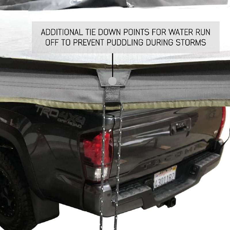 overland-vehicle-systems-nomadic-lt-270-awning-with-walls-dark-gray-open-zoomed-in-view-on-toyota-tacoma-showing-tie-downs