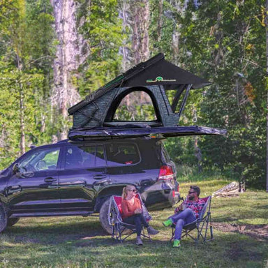 overland-vehicle-systems-xd-lohtse-hard-shell-roof-top-tent-gray-body-black-rainfly-open-side-view-on-top-ofvehicle-with-couple-in-nature