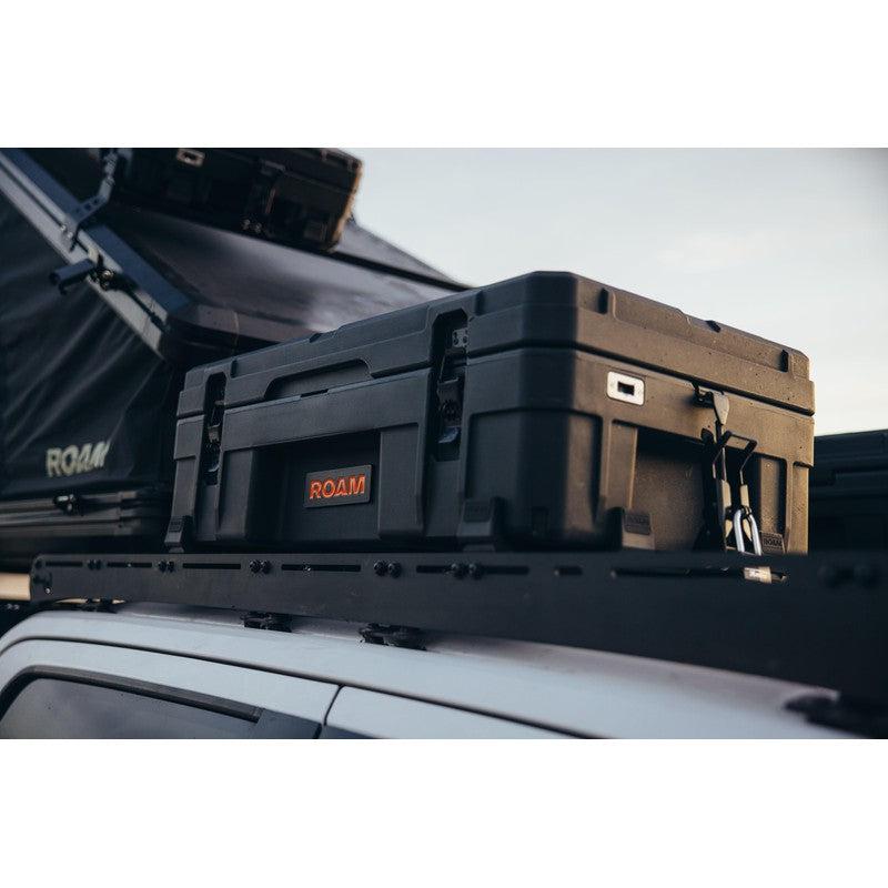 roam-66l-rugged-case-black-front-corner-view-on-roof-rack-with-rooftop-tent-in-nature