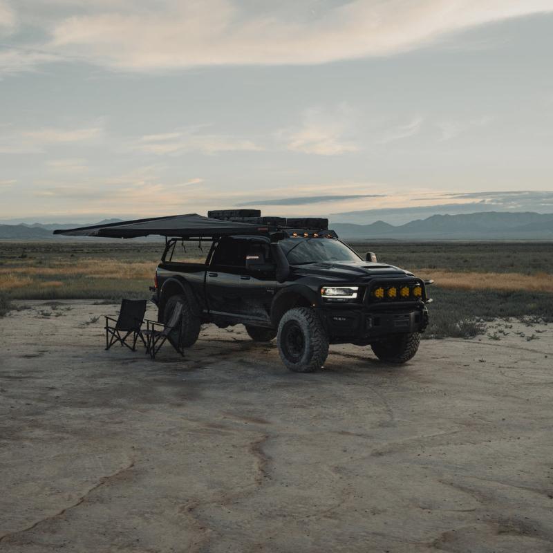 roam-arc-180-awning-open-front-corner-view-on-vehicle-with-camping-chair-in-nature