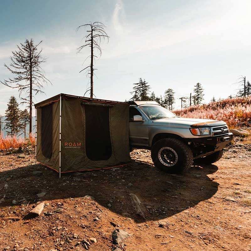 roam-standard-awning-room-forest-green-hyper-orange-front-corner-view-on-vehicle-in-nature