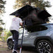 roam-vagabond-lite-rooftop-tent-black-open-front-view-on-toyota-rav4-with-person-in-nature