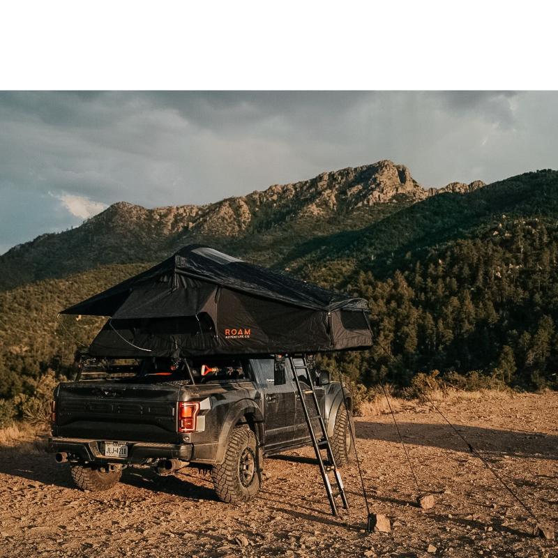 roam-vagabond-rooftop-tent-black-open-side-view-on-ford-raptor-with-ladderin-nature