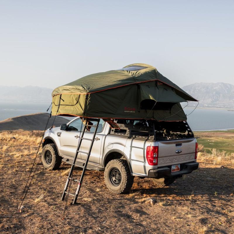 roam-vagabond-rooftop-tent-forest-green-hyper-orange-open-front-corner-view-on-ford-ranger-with-ladder-in-nature