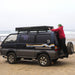 tentbox-cargo-2-hard-shell-roof-top-tent-closed-side-view-on-mitsubishi-delica-with-person-at-the-beach