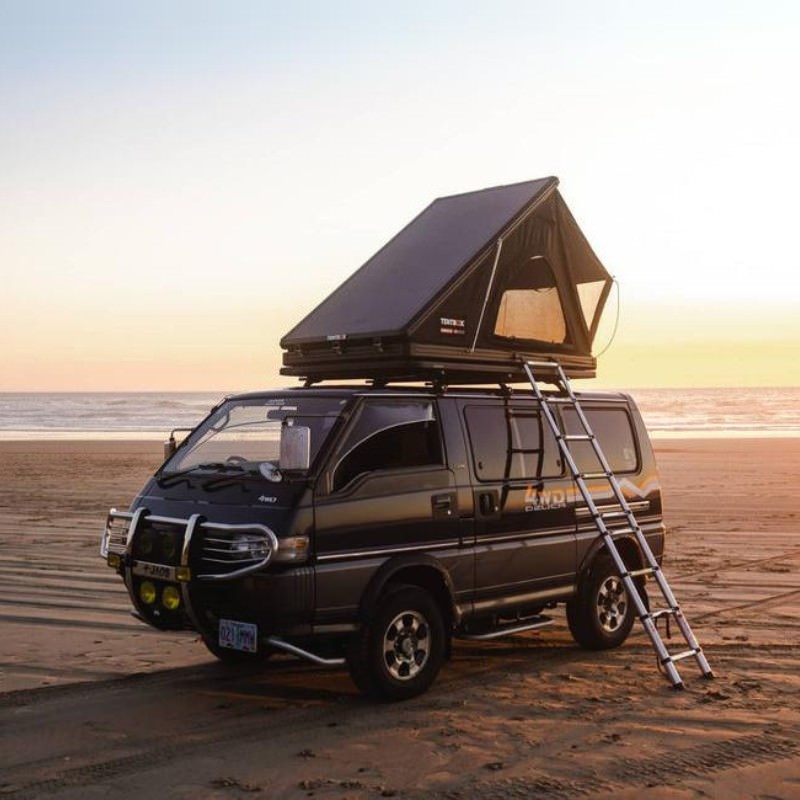 tentbox-cargo-2-hard-shell-roof-top-tent-midnight-gray-open-rear-corner-view-on-mitsubishi-delica-with-ladder-at-the-beach