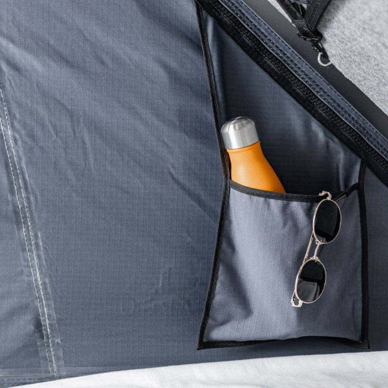 tentbox-cargo-hard-shell-roof-top-tent-black-open-close-up-view-with-sunglasses-and-bottle-inside-tent-pocket
